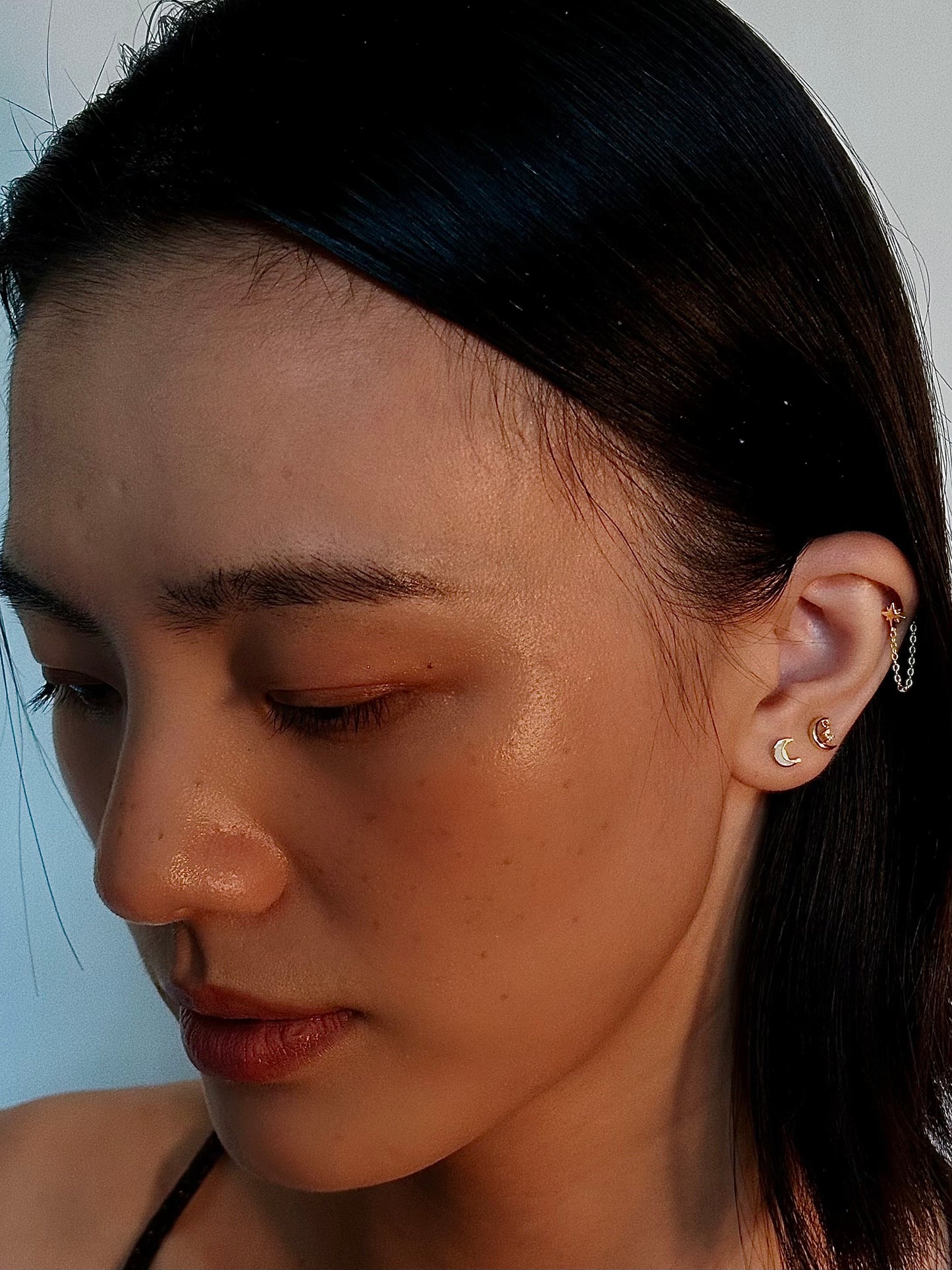Close-up side view of a model wearing the delicate star chain flatback earring, showcasing its dangling effect and how it pairs with other flatbacks.