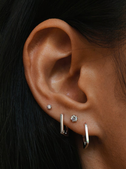 wearing the delicate 2mm & 3mm six-prong CZ flatback stud earrings in silver color on upper lobe