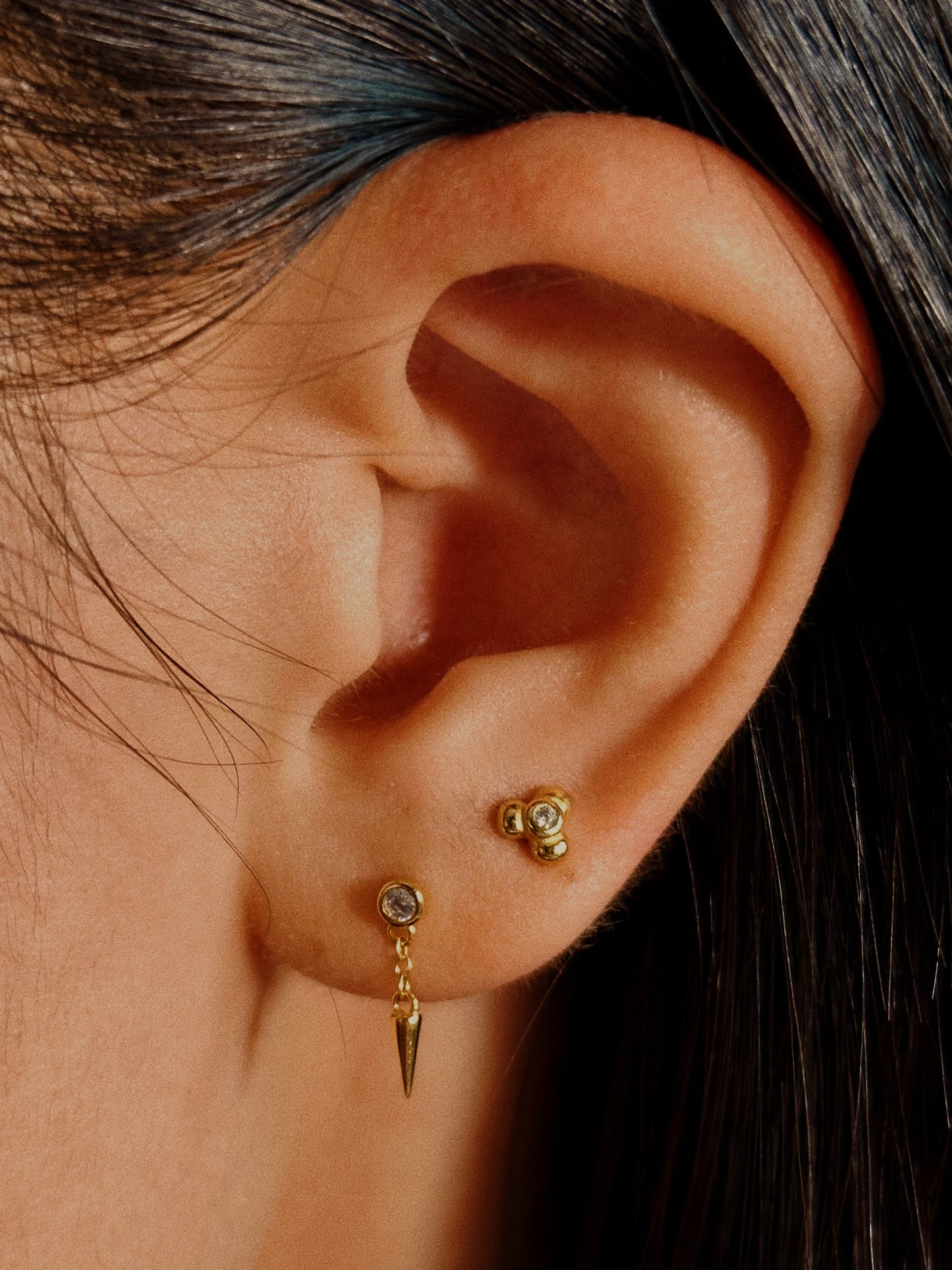 Close-up detail of the 3-petal floral motif and secure bezel setting on the sterling silver and 18k gold plated earring front