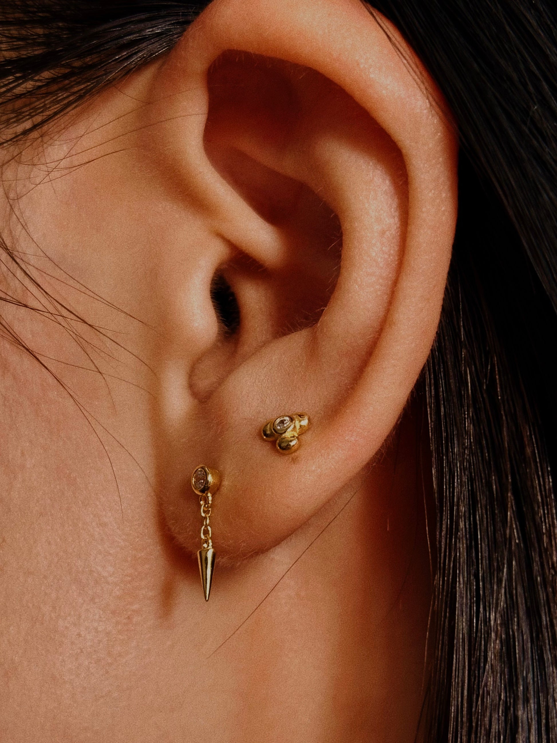 Close-up detail of the dangle spike and secure bezel setting on the sterling silver and 18k gold plated earring front
