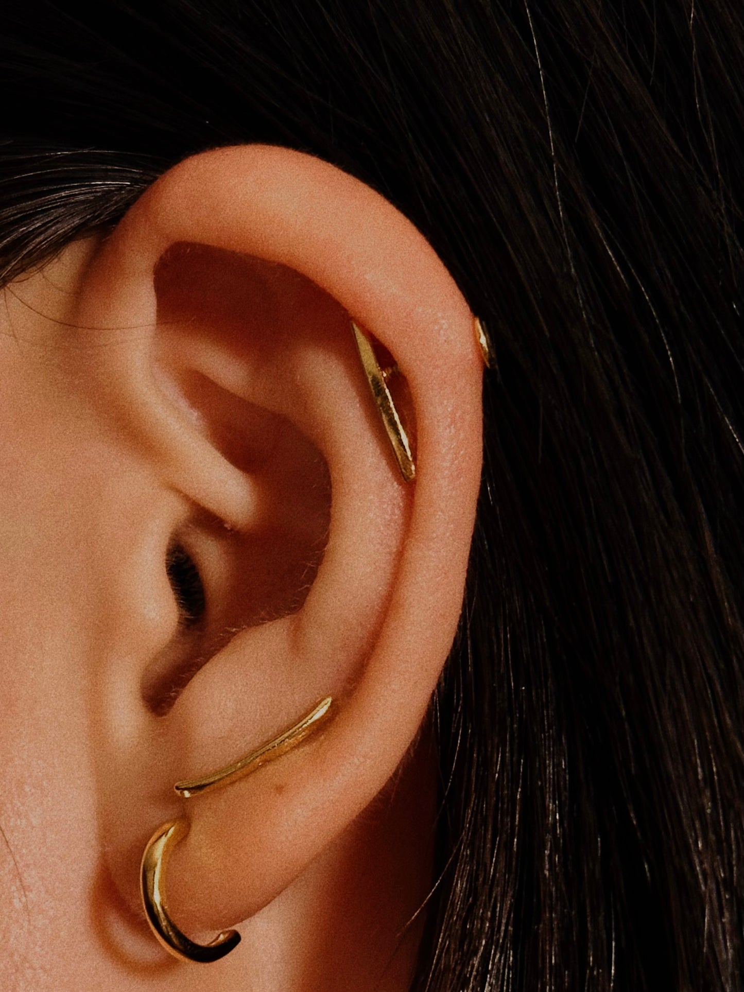 Close-up photo of a delicate crescent moon charm on a flatback earring post, made of hypoallergenic 925 silver with 18k gold plating