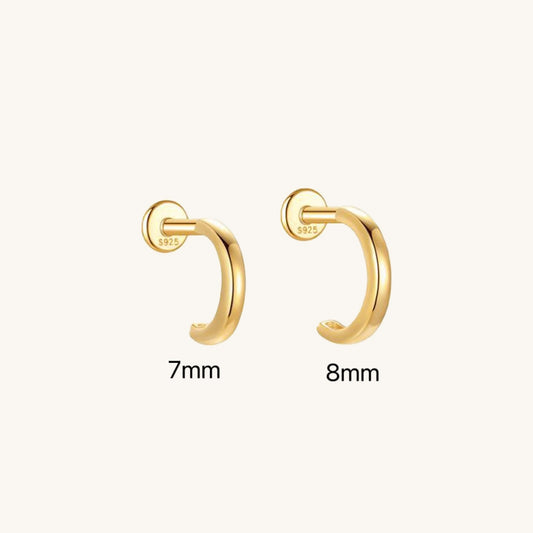 Gold huggie-style flatback earring on a neutral background, showcasing its smooth semi-circular arch design