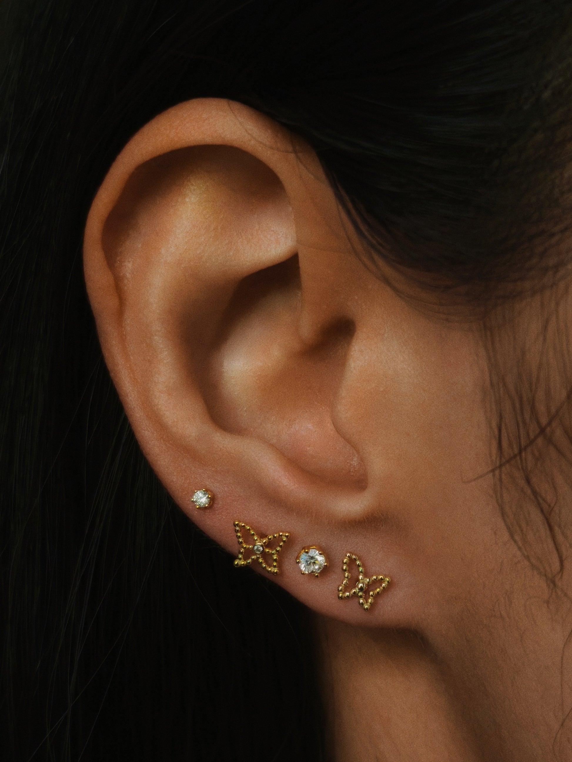 wearing the delicate 2mm & 3mm six-prong CZ flatback stud earrings in gold color on upper lobe